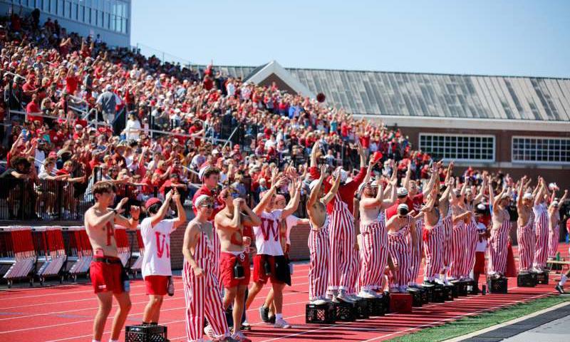 A crowd of young men stand in bleachers in Little Giant Stadium